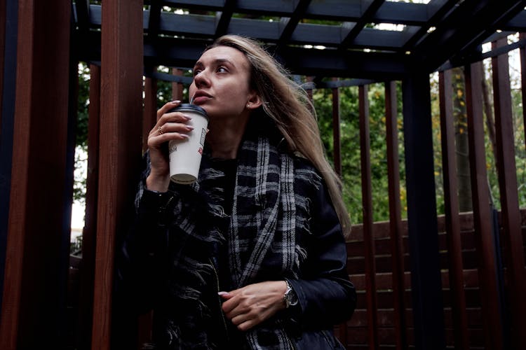 Woman Standing Outside With A Paper Cup Of Coffee