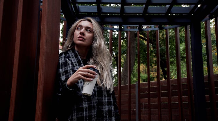 Woman Standing Outside With A Paper Cup Of Coffee