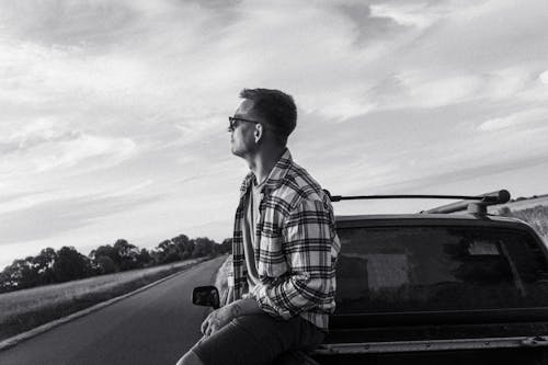 Man in a Checkered Shirt and Sunglasses Sitting on a Pickup Truck 