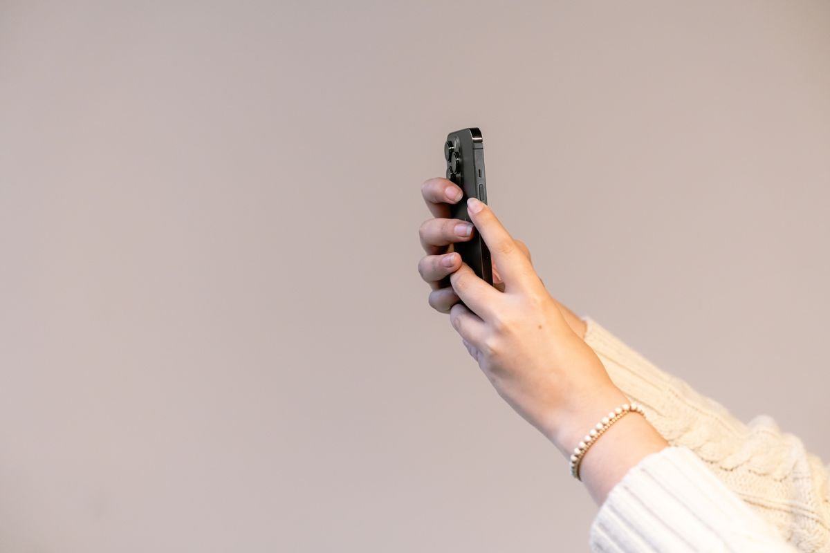 Elinde akıllı telefon tutan kişi ekrana bakıyor, odaklanmış ifade