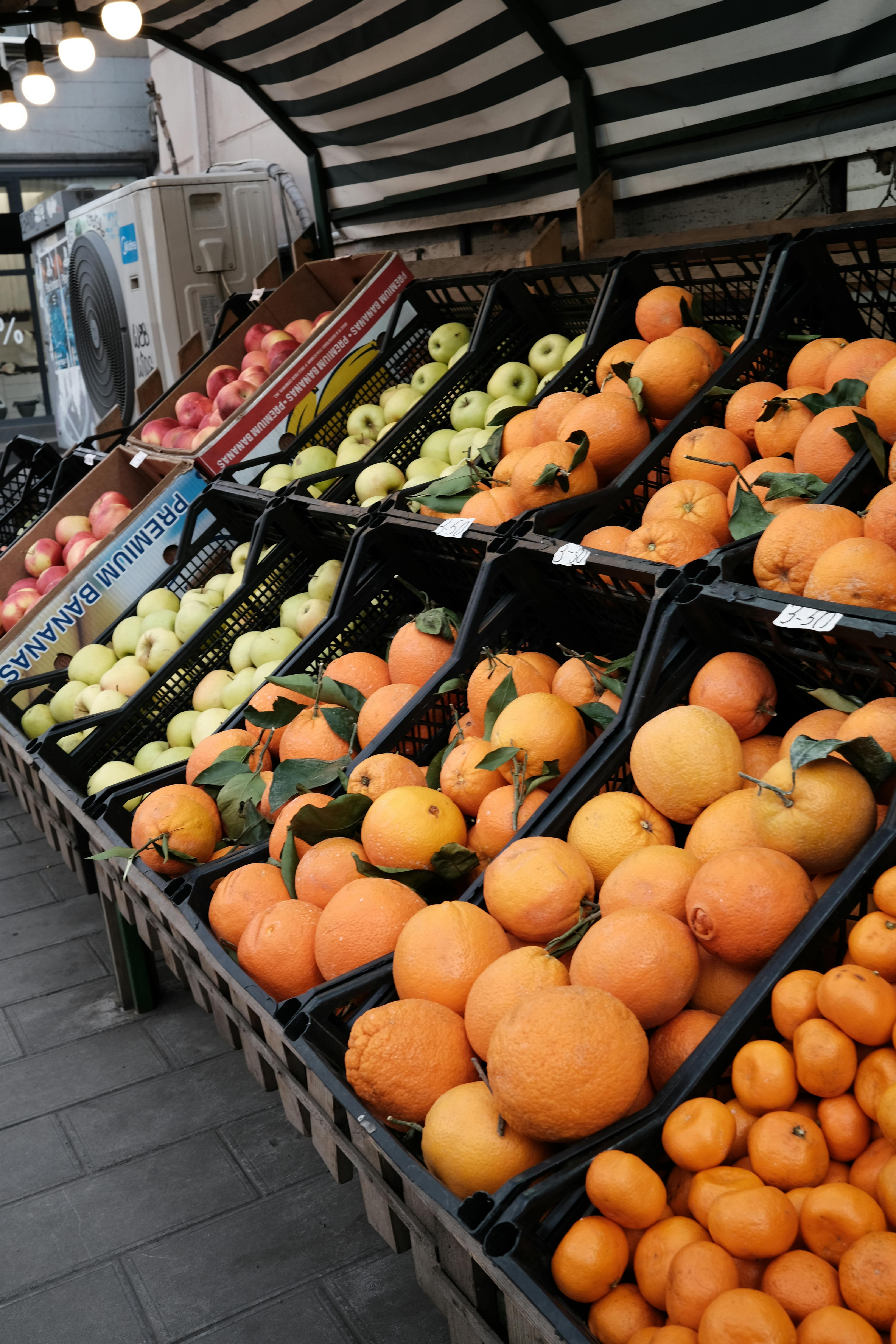 a fruit stand with oranges and apples in the baskets