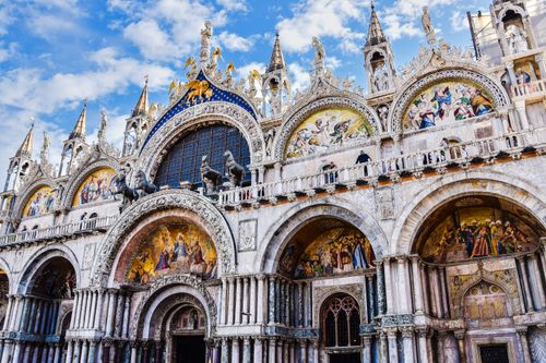 Free Ornately detailed facade of St. Mark's Basilica under a blue sky in Venice, Italy. Stock Photo