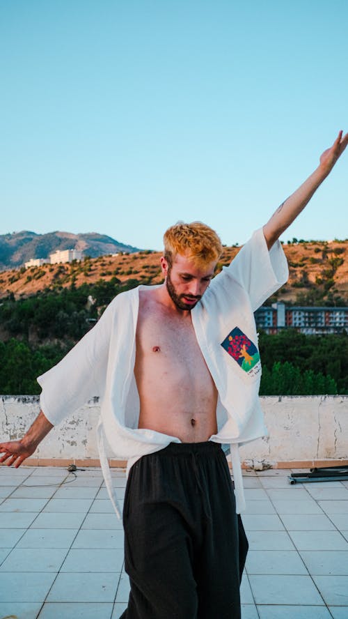 Bearded Man in Unbuttoned White Shirt Dancing on Terrace