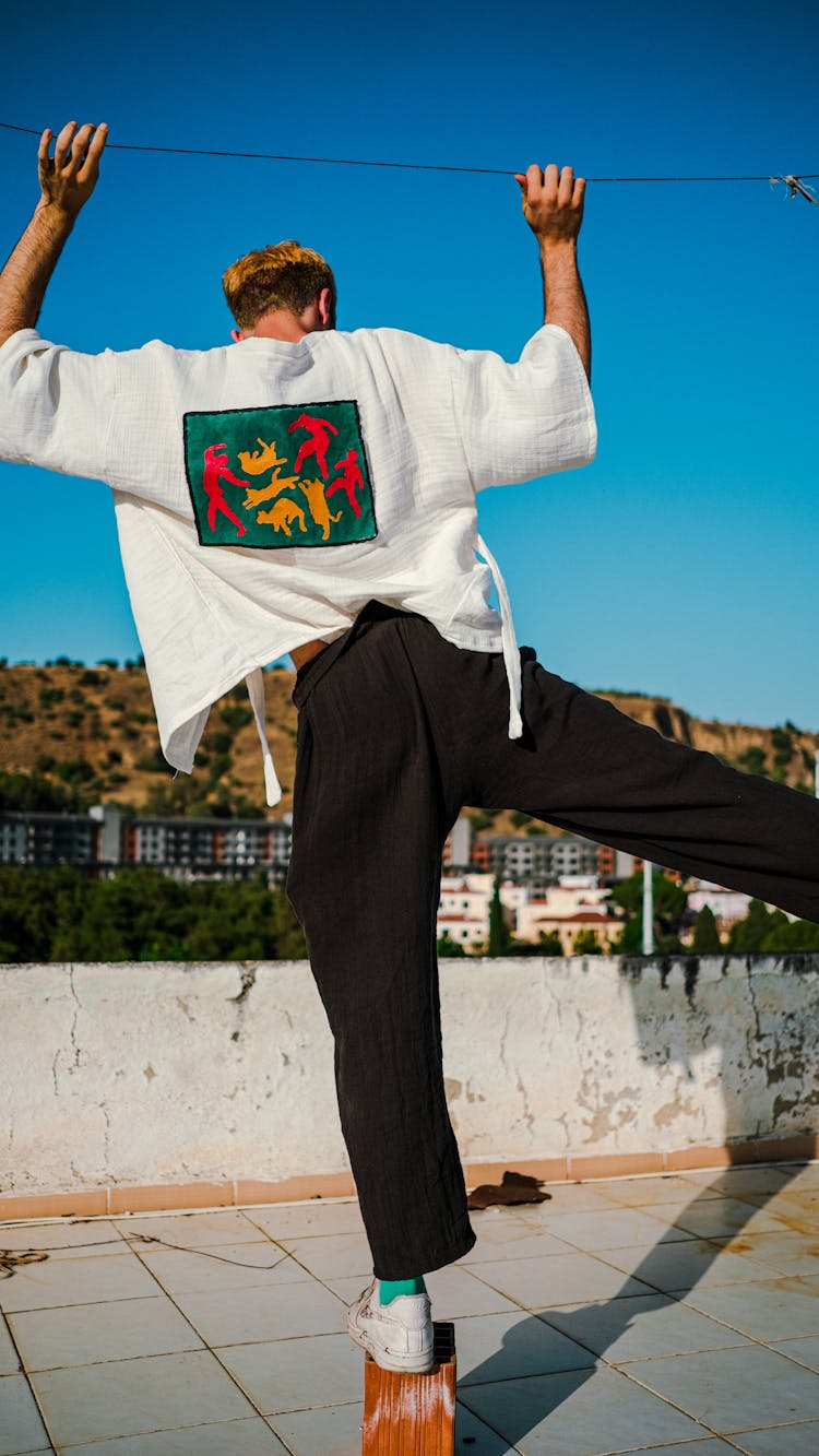 Man In White Shirt And Black Pants Balancing On One Leg