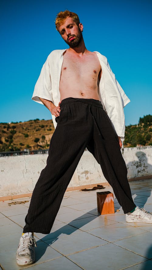 Young Man in White Shirt and Black Pants Posing on a Roof