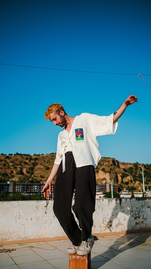 Man in White Shirt and Black Pants Balancing on a Block