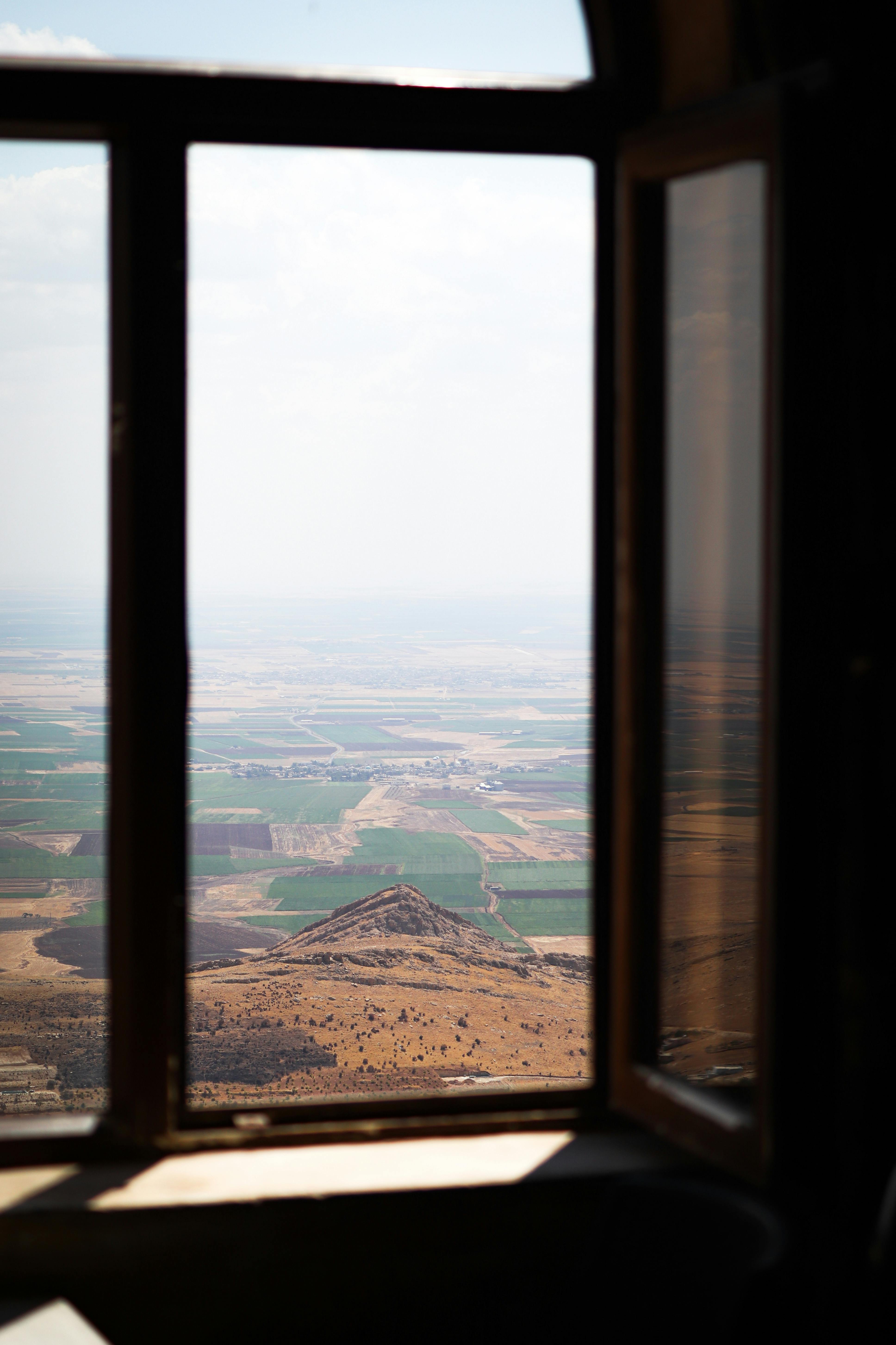 A picturesque view of Mardin's rural landscape through an open window.