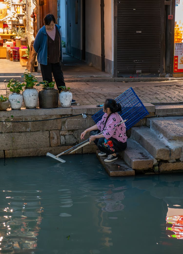 Women Cleaning Street By The River