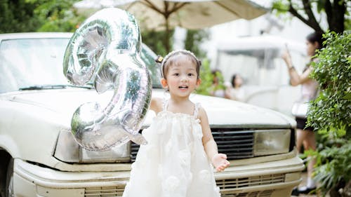 A Little Girl in a Dress Holding a Balloon