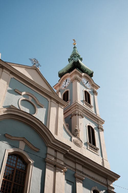 Free Capture of a historic Gothic church with clock tower in Budapest, Hungary under a clear blue sky. Stock Photo
