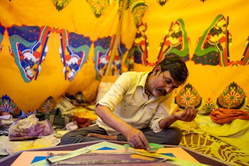 Indian Man Sitting Crossed-Legged and Using Yellow Powder