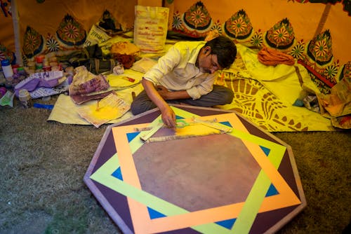 Man Sitting Crossed-Legged and Working on a Painting 