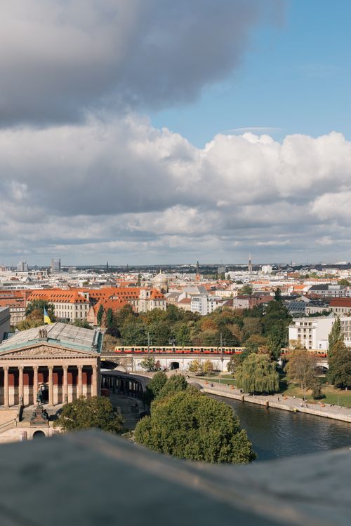 Free A captivating view of Berlin featuring urban architecture and a passing train on a sunny day. Stock Photo