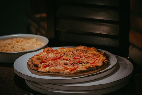 Free Delightful freshly baked homemade pizza with tomato slices and cheese, perfect for a cozy evening meal. Stock Photo