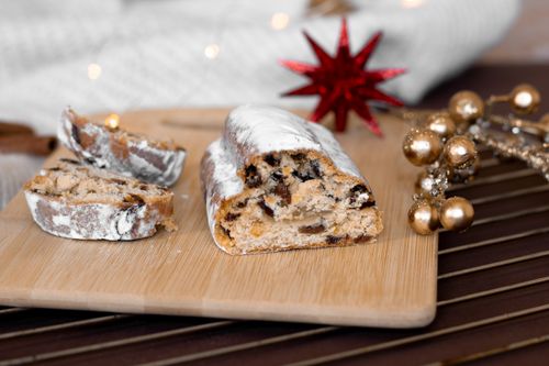 Free Festive Christmas fruitcake dusted with powdered sugar on a wooden board, perfect for holiday celebrations. Stock Photo