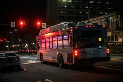 Free A city bus stopped at a traffic light during the night in an urban downtown setting. Stock Photo