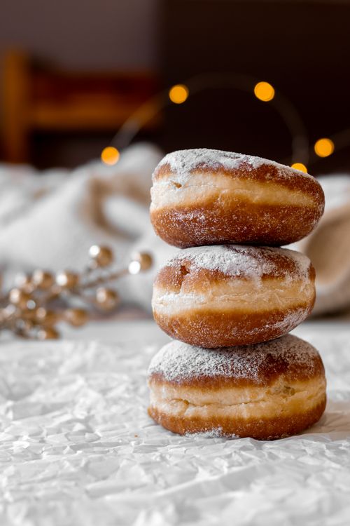 Free A mouthwatering stack of sugary doughnuts dusted with powdered sugar, perfect for dessert lovers. Stock Photo
