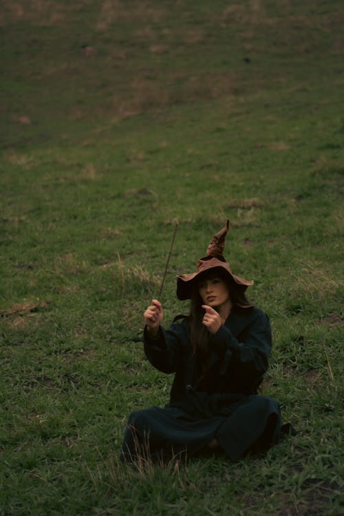 Woman in a Witch Costume Sitting on the Grass