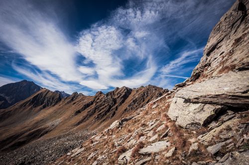Free Breathtaking view of rocky mountain terrain with dramatic clouds and clear blue sky. Stock Photo