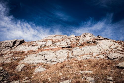 Free A rugged rocky cliff against a vibrant blue sky, showcasing natural geological formations. Stock Photo