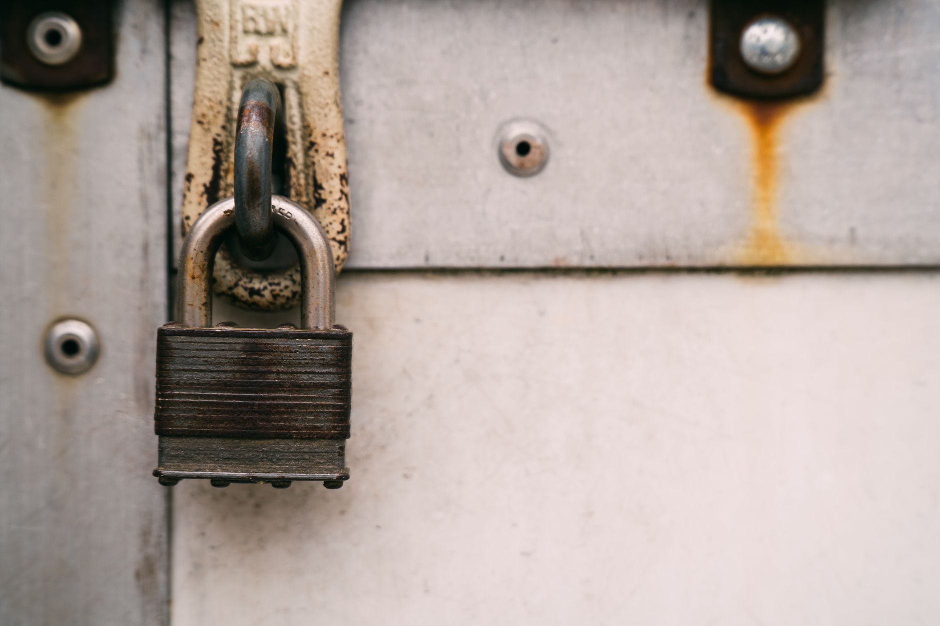Close-up of a rusty metal padlock on a weathered door, highlighting security and decay.