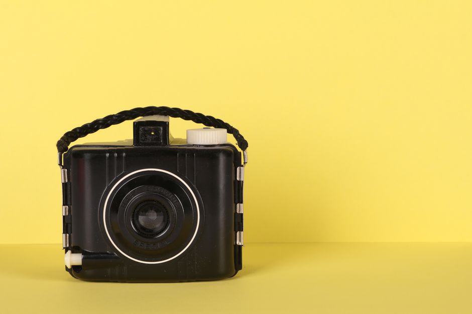 Classic vintage camera against a bright yellow backdrop, showcasing timeless design.
