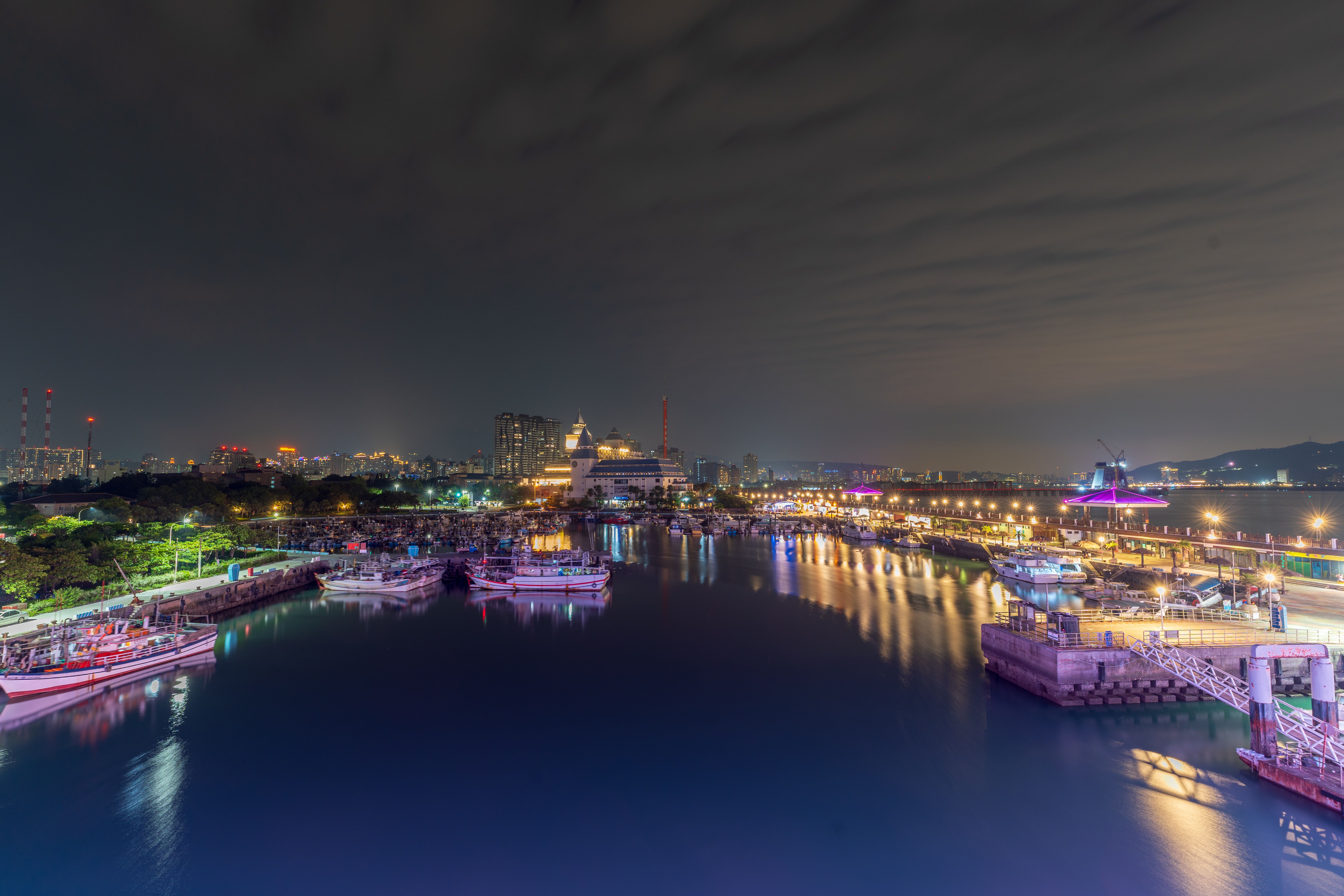 Stunning view of a vibrant city harbor with illuminated buildings and reflections at night.