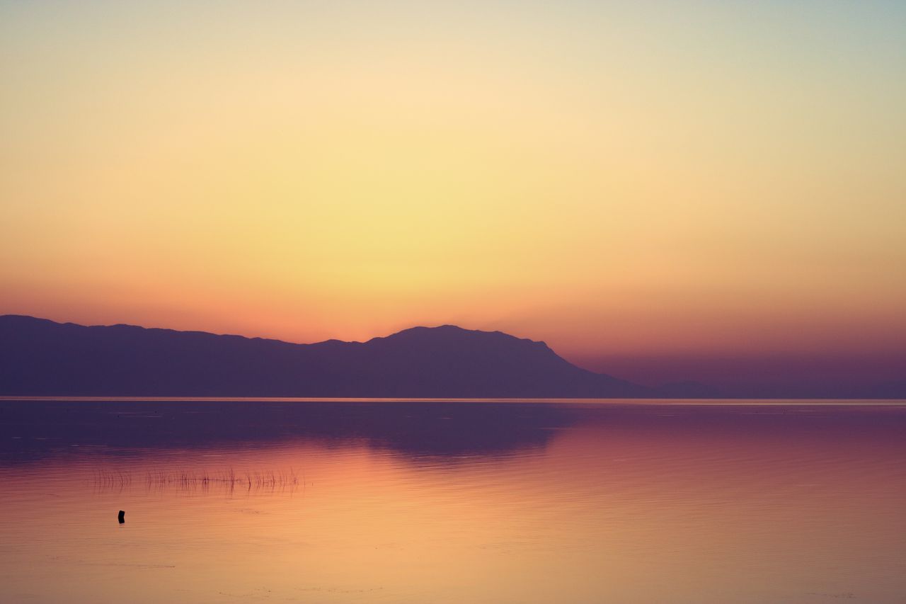 Peaceful sunset reflecting over a calm mountain lake, ideal for wallpaper