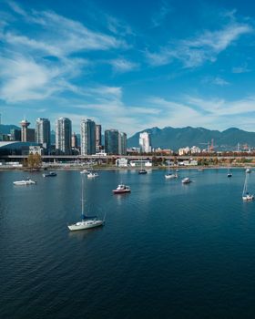 A stunning aerial view of Vancouver Harbor featuring sailboats against a backdrop of the city's skyline and mountains.