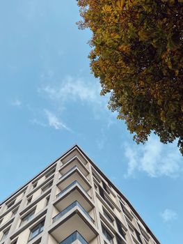Contemporary apartment building with autumn foliage and bright blue sky.