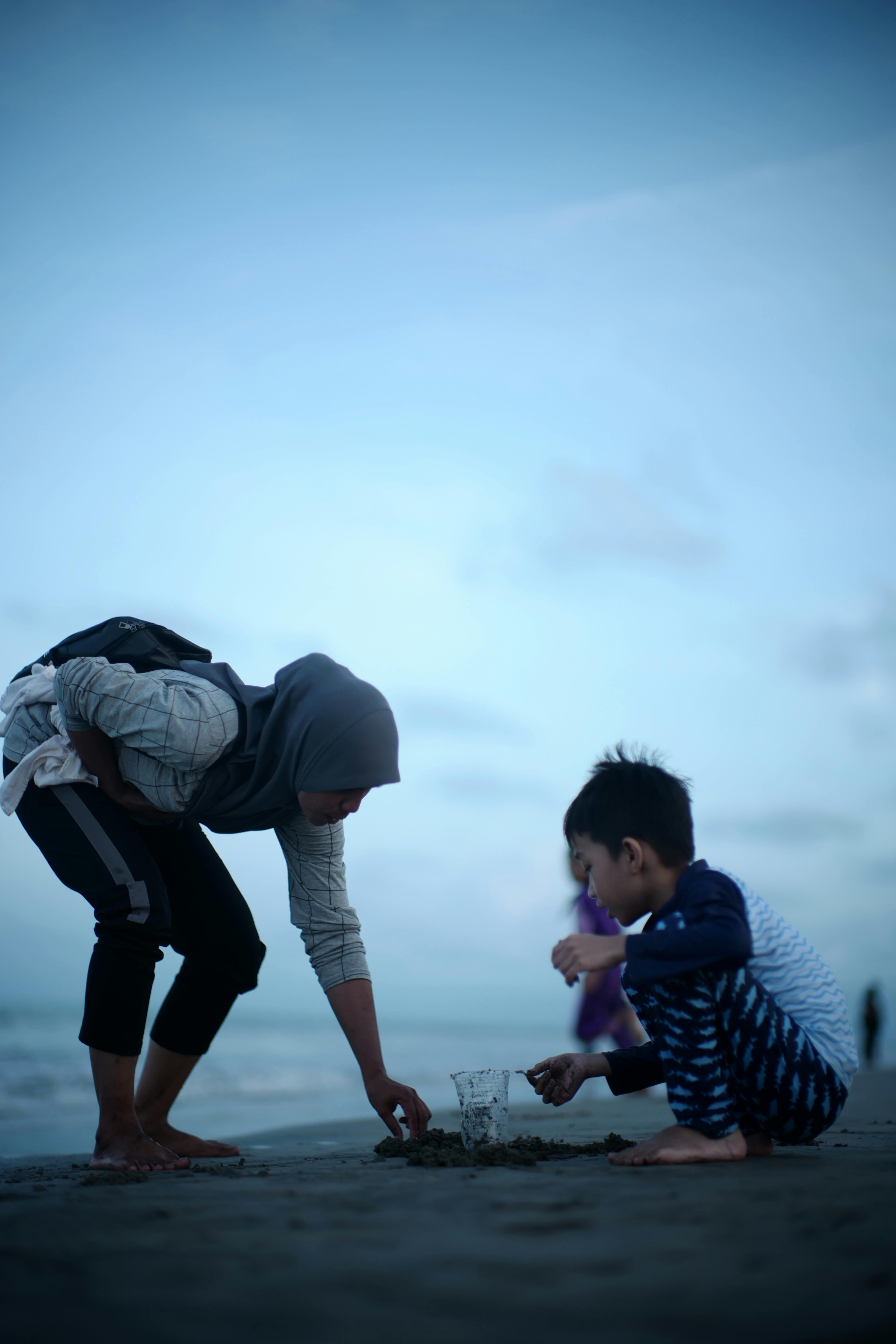 mother and son playing with sand on the beach