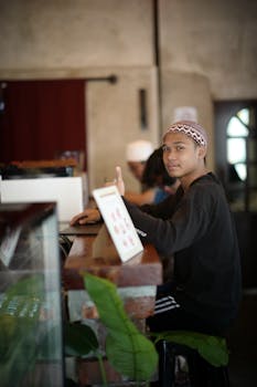 Teenager sitting at a brick café counter in Muar, Malaysia, engaged in conversation.