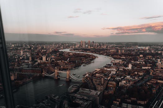 Captivating aerial view of London's skyline with the iconic Tower Bridge over the Thames River at sunset.
