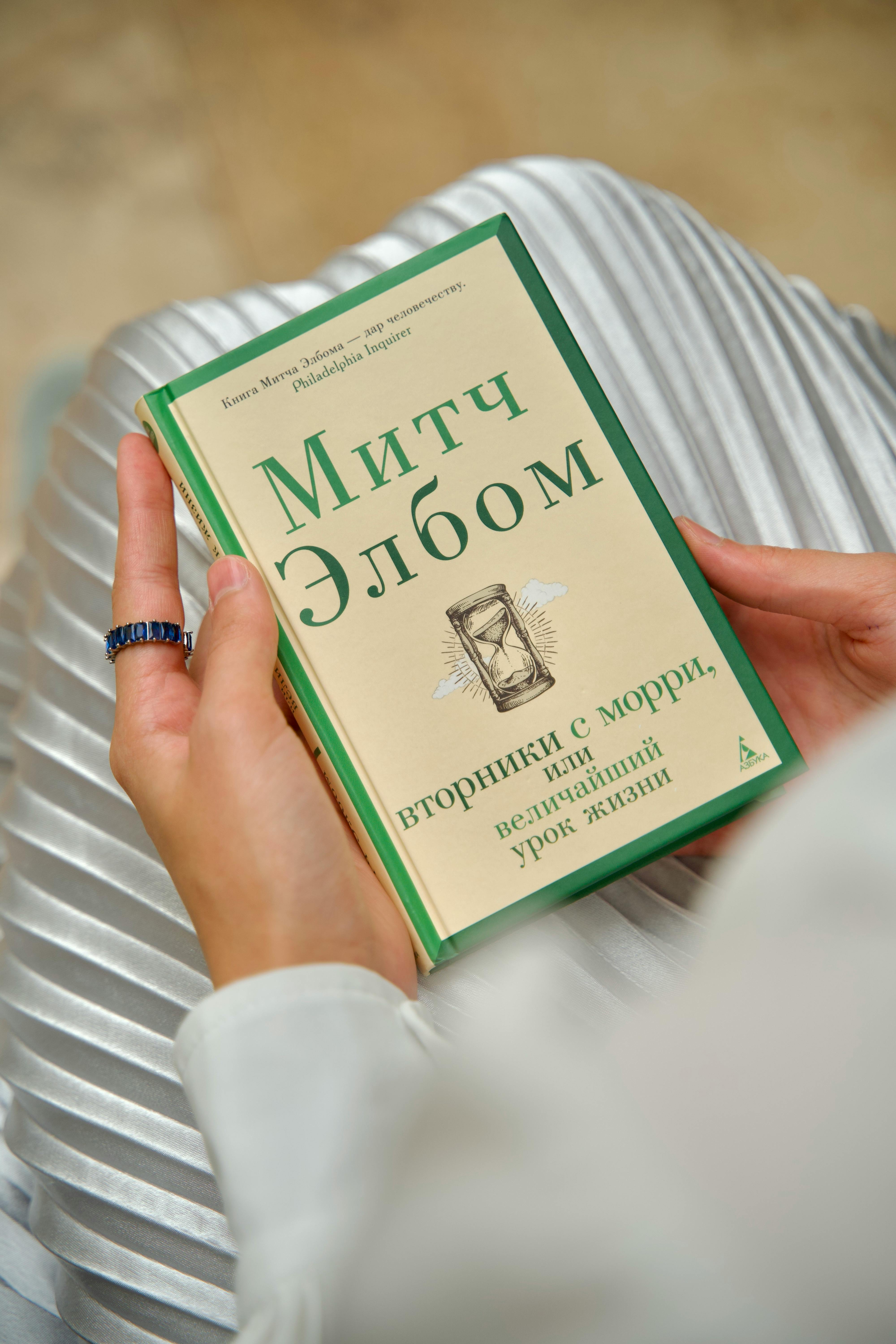 Close-up of a woman holding a book with Russian text, offering a peaceful reading moment.