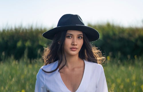 Portrait of a Young Woman Wearing a Hat Standing on a Meadow 