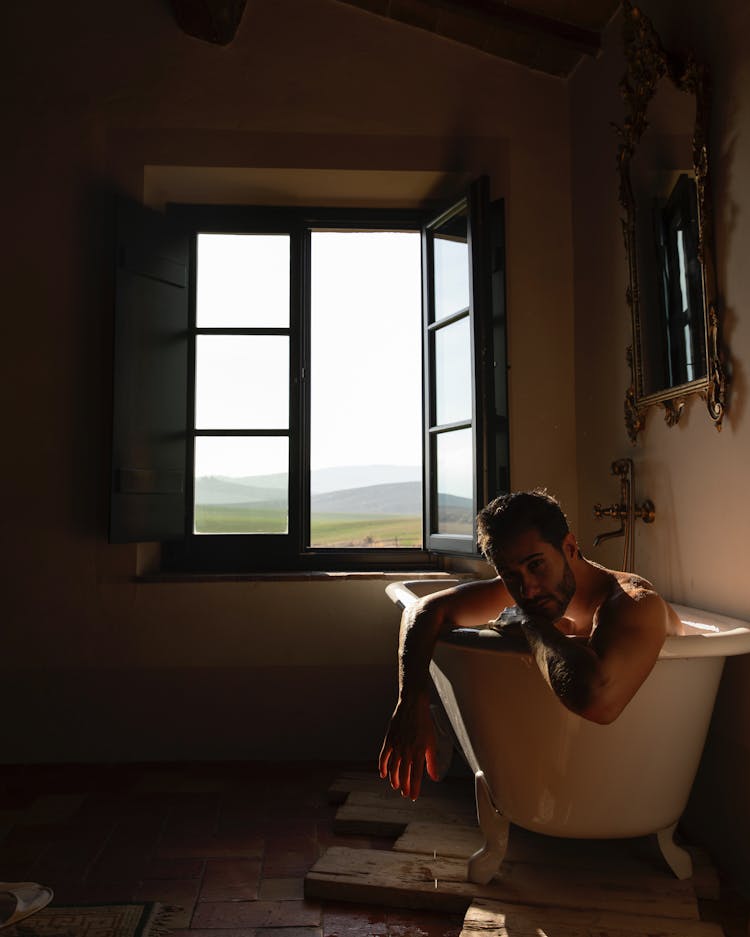 Man Sitting In A Bath By The Window 