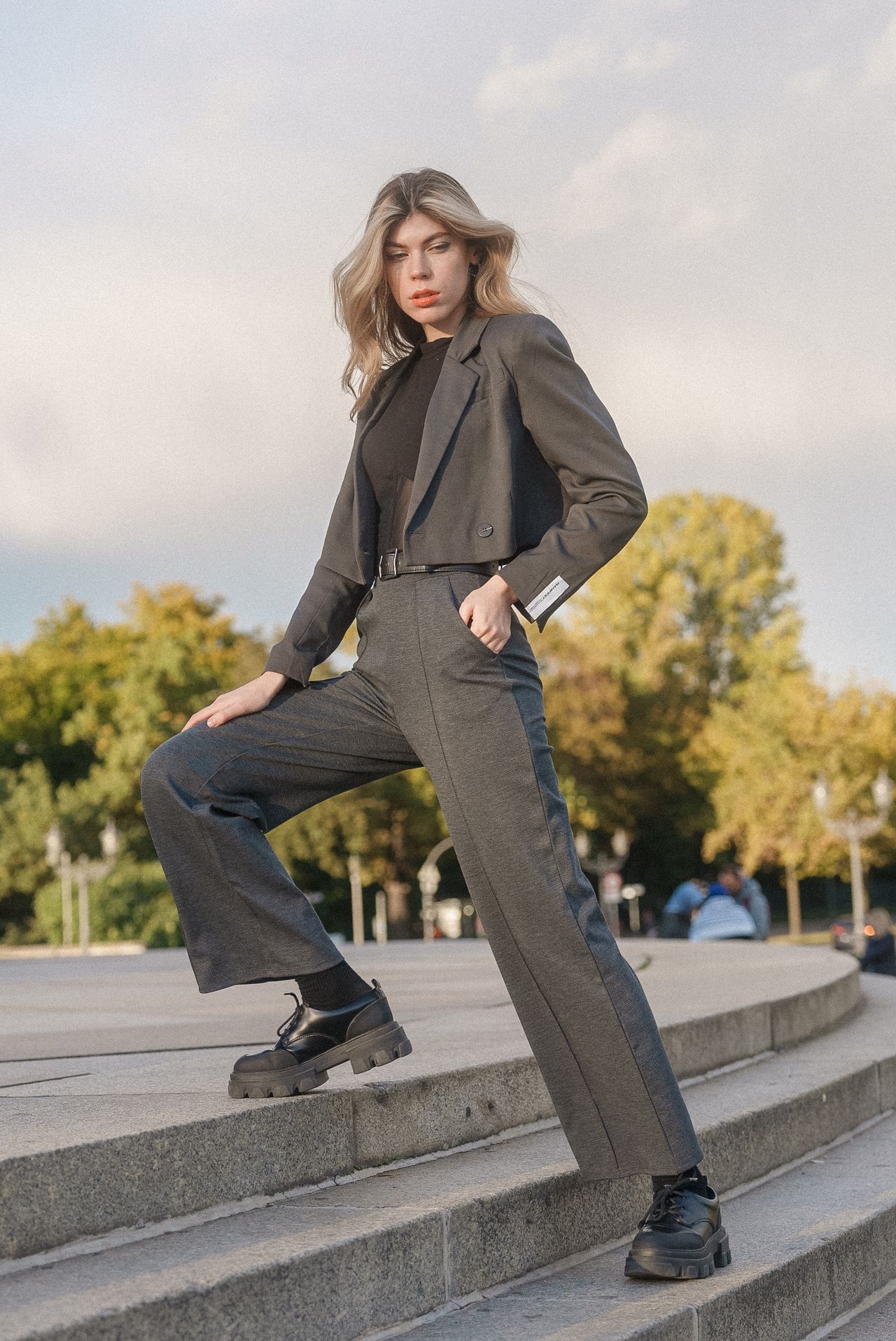 Woman wearing a cropped gray blazer with matching wide-leg trousers, a black top and chunky black loafers