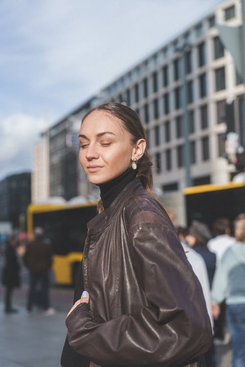 Young Woman in Brown Leather Jacket with Closed Eyes on the Sidewalk