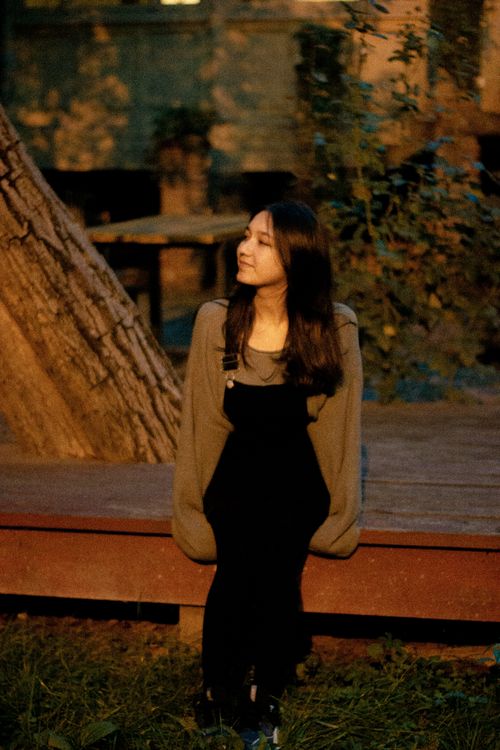 Free Young woman sitting on a bench during a calm autumn evening in a park. Stock Photo