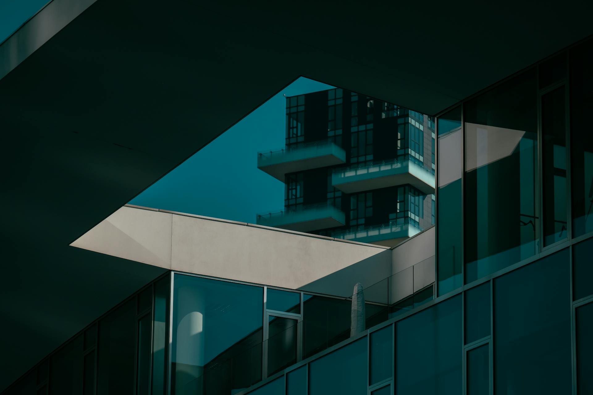 Modern building facade featuring geometric lines and glass reflections in an urban setting.