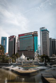 Scenic view of Kuala Lumpur's skyline featuring modern skyscrapers and the historic Jamek Mosque.