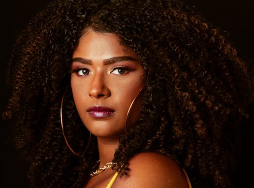 Portrait of a Young Woman with Curly Hair Wearing Makeup and Hoop Earrings 