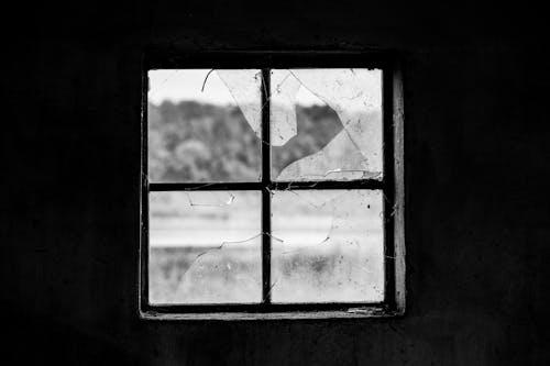 Black and White Photo of Broken Window Pane in Abandoned House