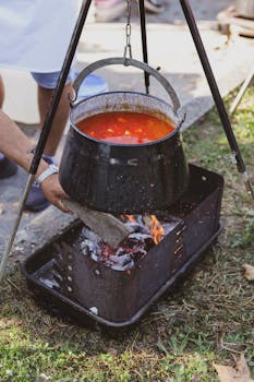 A man stirs a pot of soup hanging over a fire outdoors in Pakrac, Croatia.
