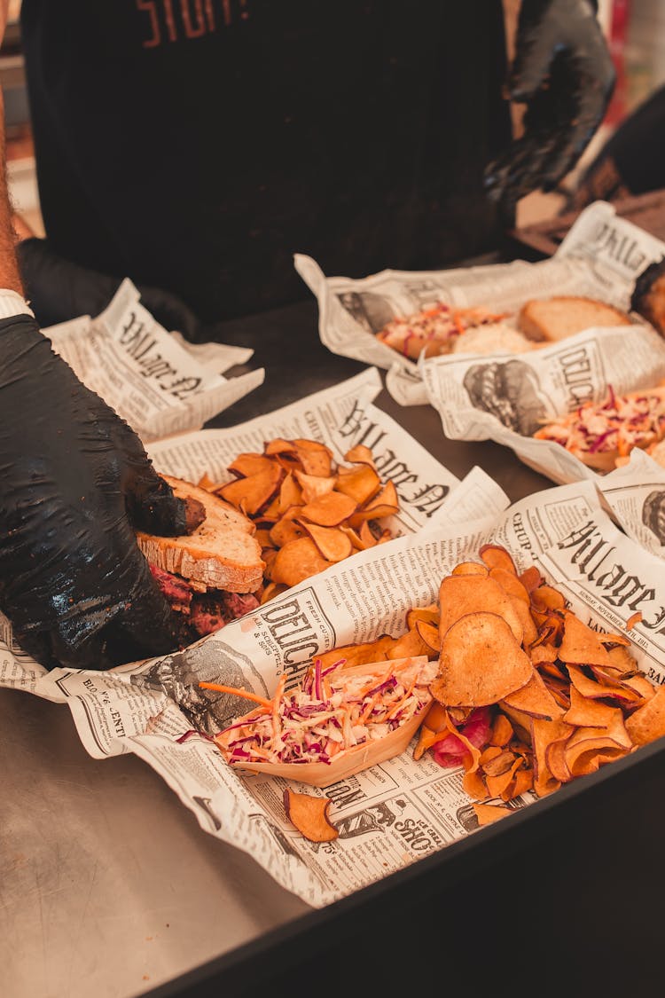 Hands Of A Person Preparing Chips And Sandwiches