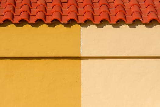 Bright yellow and orange wall with a red tiled roof, showcasing vibrant architecture.