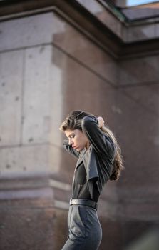 Stylish young woman adjusting her hair in an urban setting.