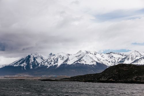 Free Dramatic snowy Andes mountains under cloudy skies in Ushuaia, Argentina. Stock Photo
