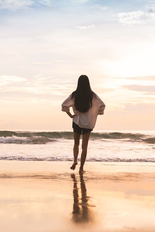 Free A woman enjoys a tranquil morning walk by the sea on Da Nang beach, Vietnam. Stock Photo