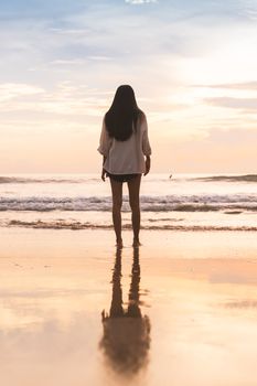 A woman stands on Da Nang beach at sunrise, enjoying the serene ocean view.